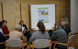 Udeleženci sedijo v polkrogu ob predstavitvi projekta.