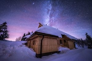 koča na Veliki planini pozimi, v ozadju zvezdnato nebo.
